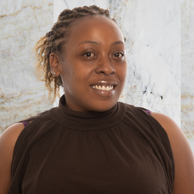 A woman with braided hair, wearing a sleeveless brown turtleneck top, smiles at the camera against a white and gray marble background.