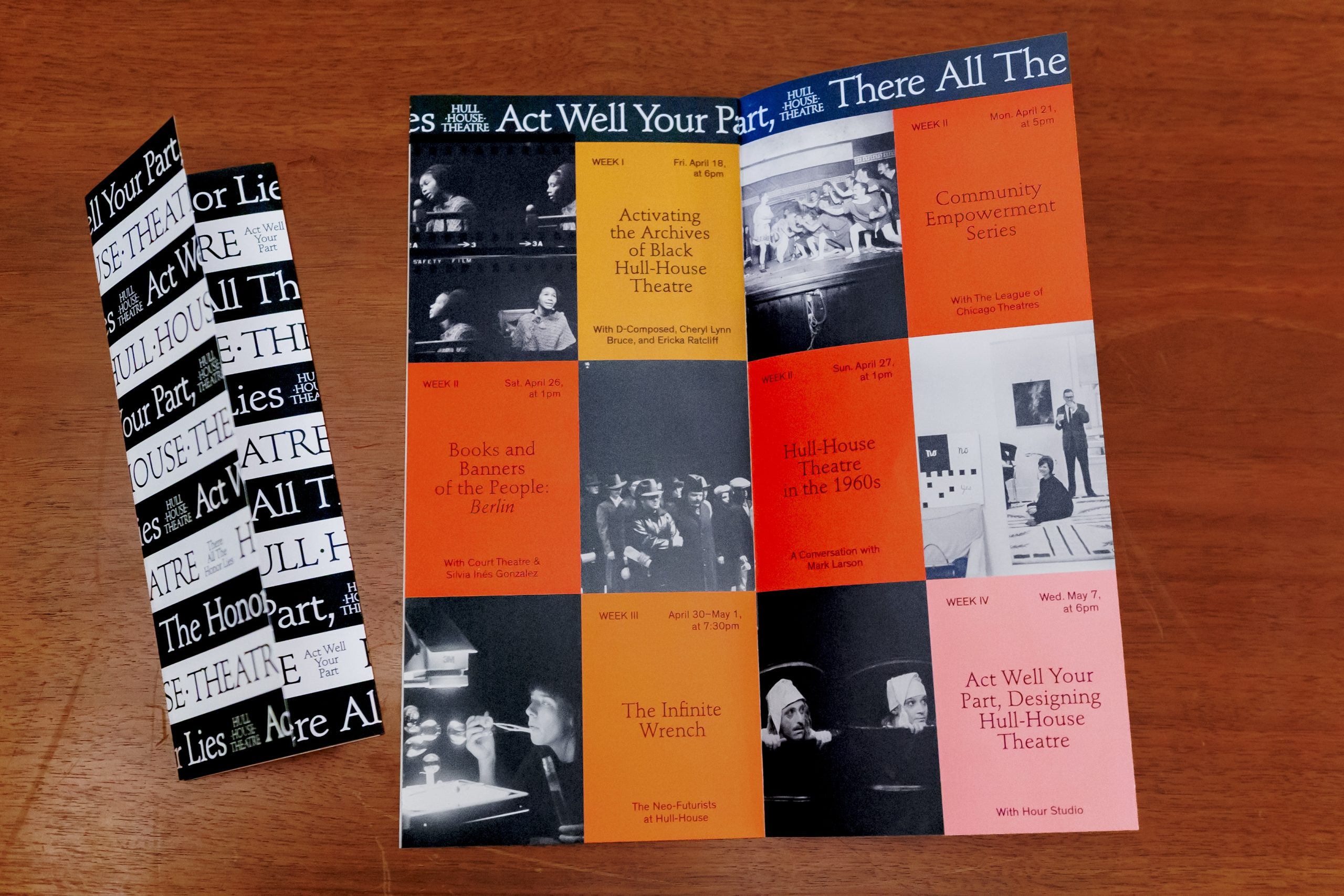 A brochure is open on a wooden table, displaying a schedule of theater-themed events in colored blocks with photos and text. Beside it is a closed, folded brochure with black-and-white text strips on the cover.