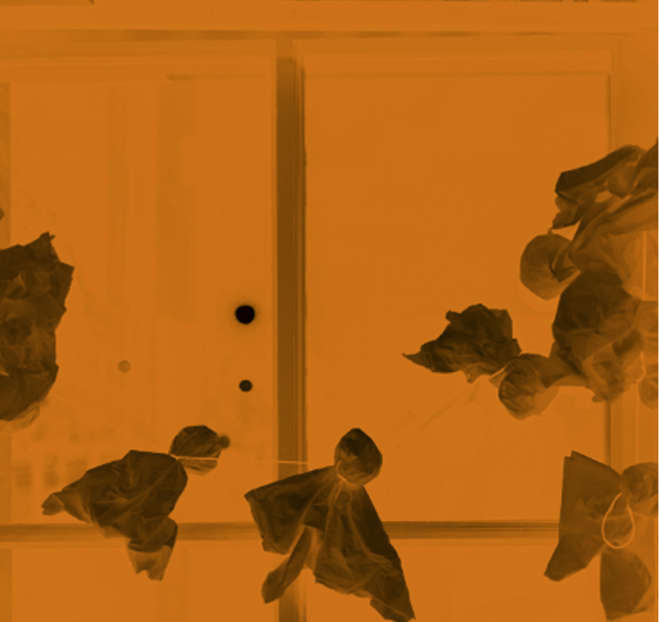 Ghost-shaped decorations hang by strings in front of a window, with an orange filter covering the image, giving it a Halloween-themed appearance.