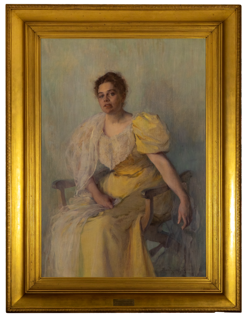 A painted portrait of a seated woman wearing a yellow dress with puffed sleeves, draped with a sheer white scarf. She has short brown hair and looks calmly at the viewer. The painting is set in an ornate gold frame.