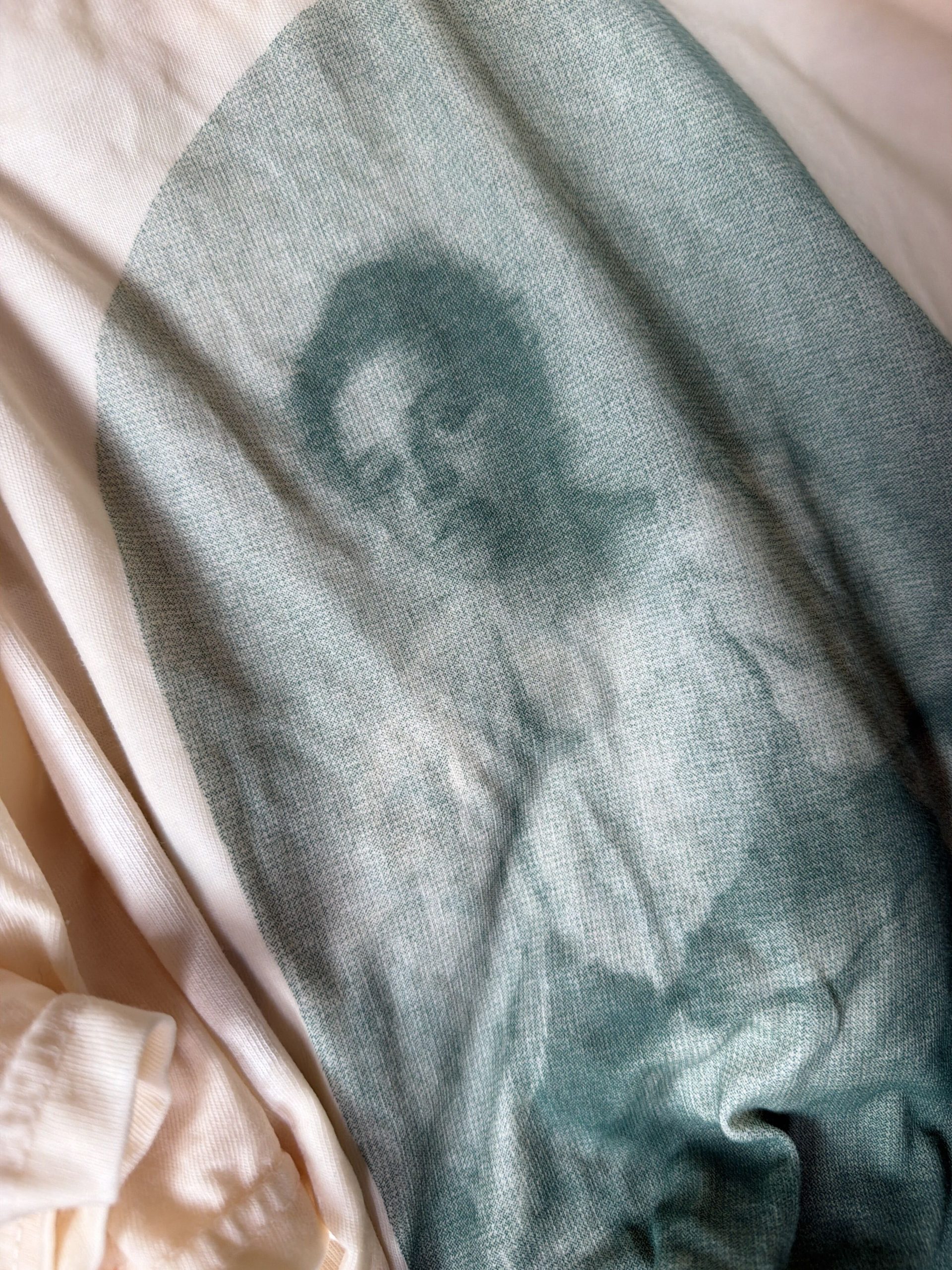 A vintage-style photograph of a woman is printed on a piece of white fabric with gentle folds and creases, creating a soft, faded effect.